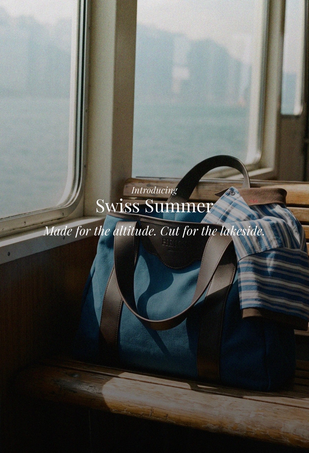 HEIGS Swiss Summer editorial — the à New York Tote Bag in Indigo with a striped shirt at the ferry window. Made for the altitude, cut for the lakeside