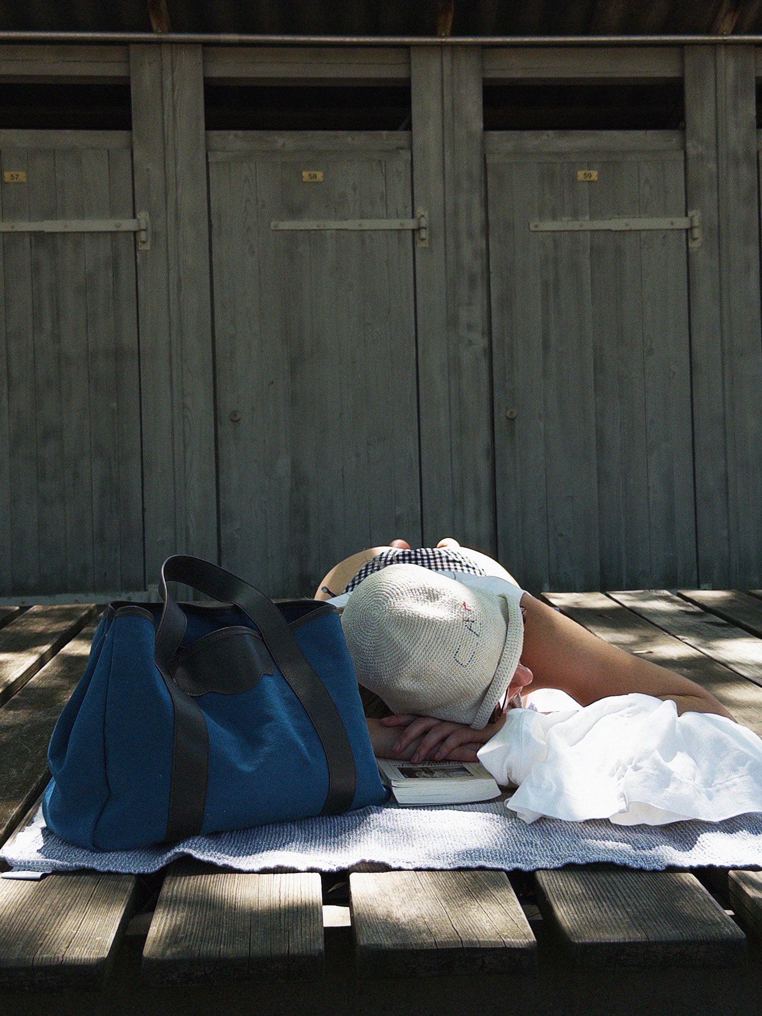 The à New York Tote Bag in Indigo resting beside a bather on a sunlit boardwalk — HEIGS summer editorial