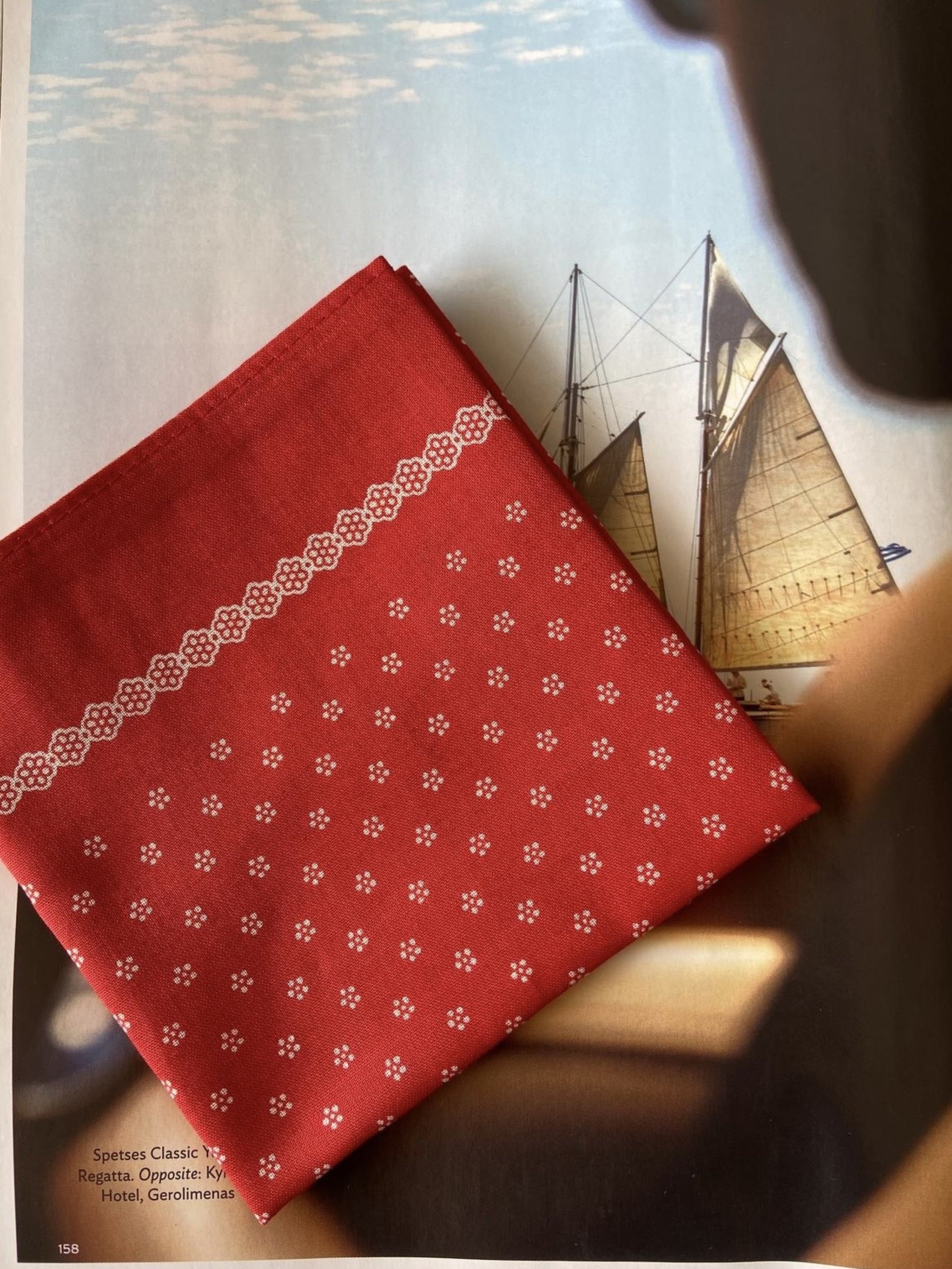 The Glarner Tuechli folded, showing the white floral print and scalloped border of the red Swiss cotton cloth
